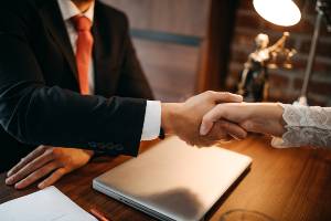 man in suit shaking hands with woman next to small statue